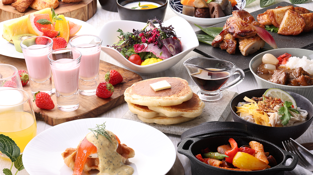 テーブルに並べられた様々な朝食メニュー。クロワッサン、サラダ、ソーセージ、卵料理、フルーツなどが並ぶ。